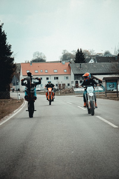 2 man dressed in red during the day on the road to ride a bicycle
